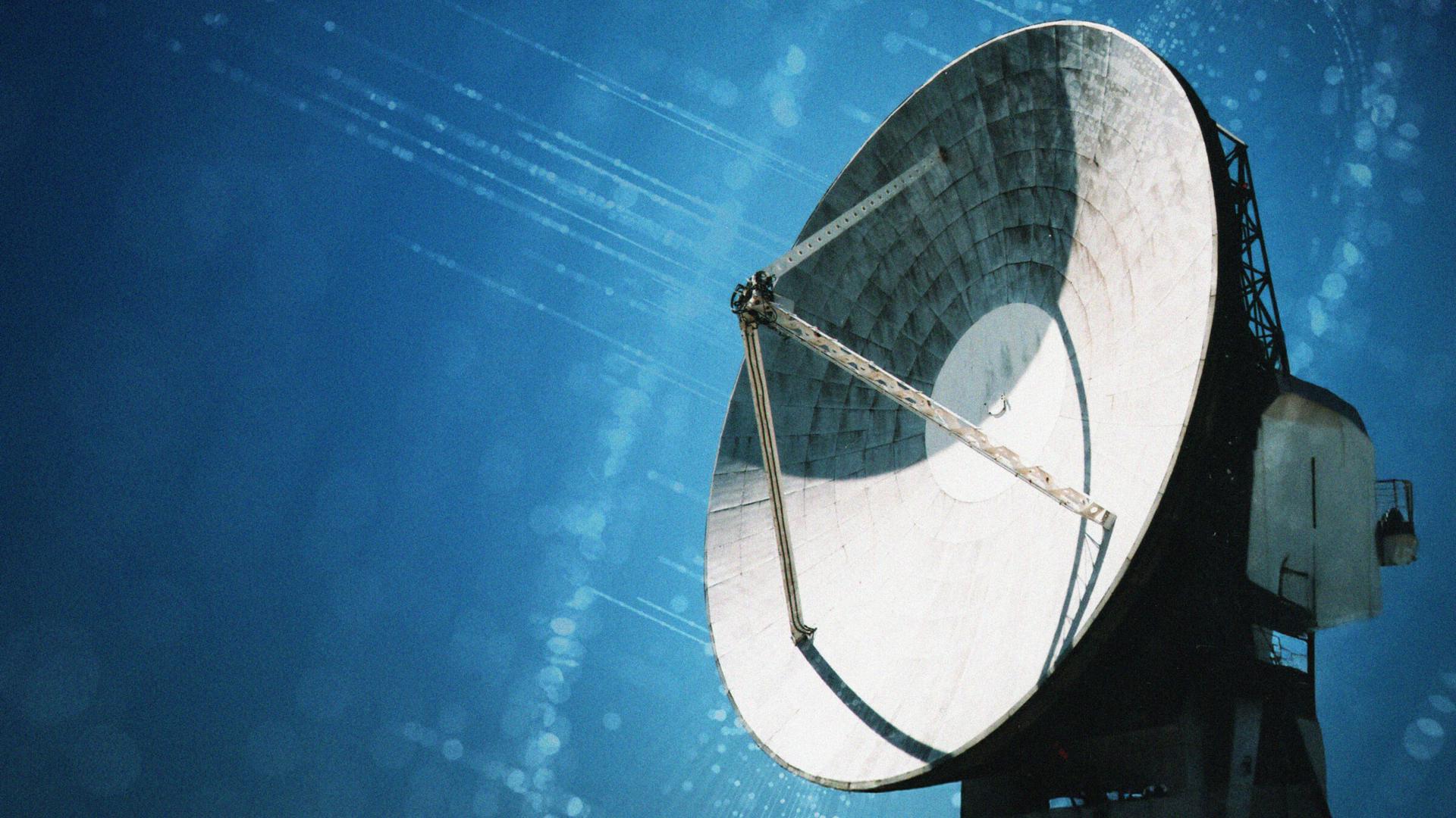 Large satellite dish against a clear blue sky, with sunlight reflecting off its surface, capturing a sense of communication and technology.