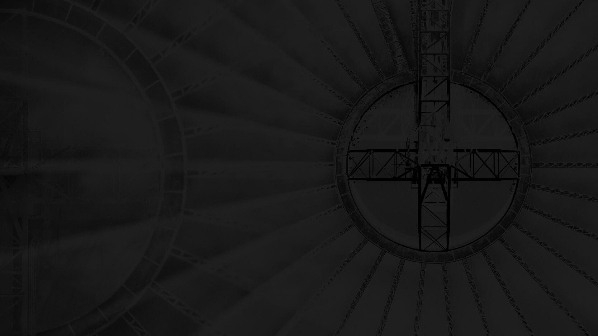 Abstract image of a circular structure with radial beams and a central metal framework, resembling an industrial design or architectural detail.