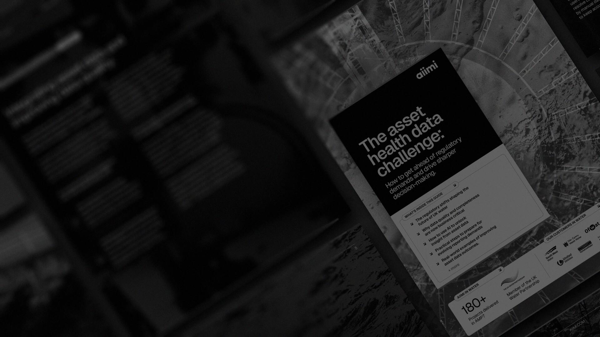 Close-up of a brochure titled "The Asset Health Data Challenge," discussing regulatory demands and decision-making, with various logos at the bottom.