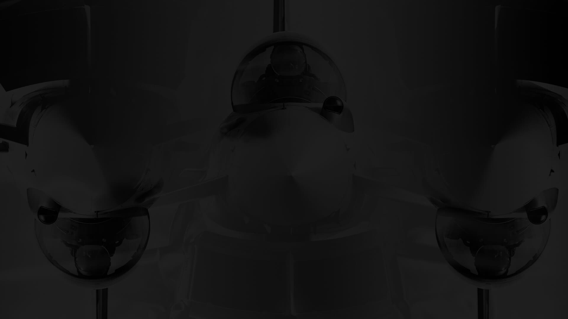 A dark, shadowy image of a fighter jet viewed from the front, highlighting its cockpit and twin engines.