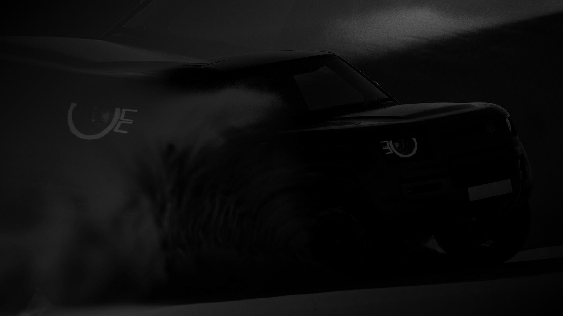 A dark, shadowy image of a vehicle drifting through sand with visible tire tracks and illuminated headlights.