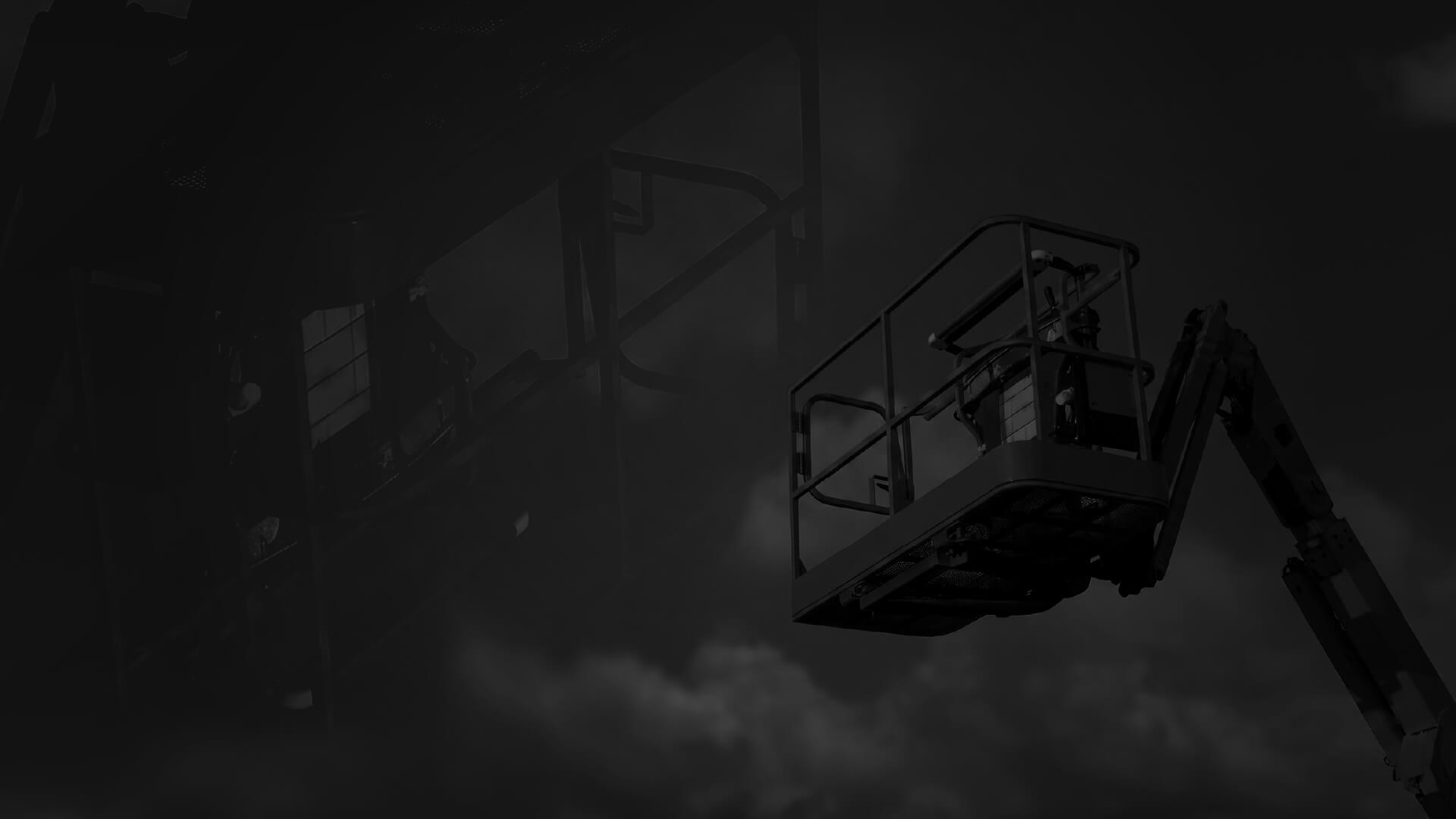 A dimly lit scene showing an elevated work platform or cherry picker against a cloudy sky.