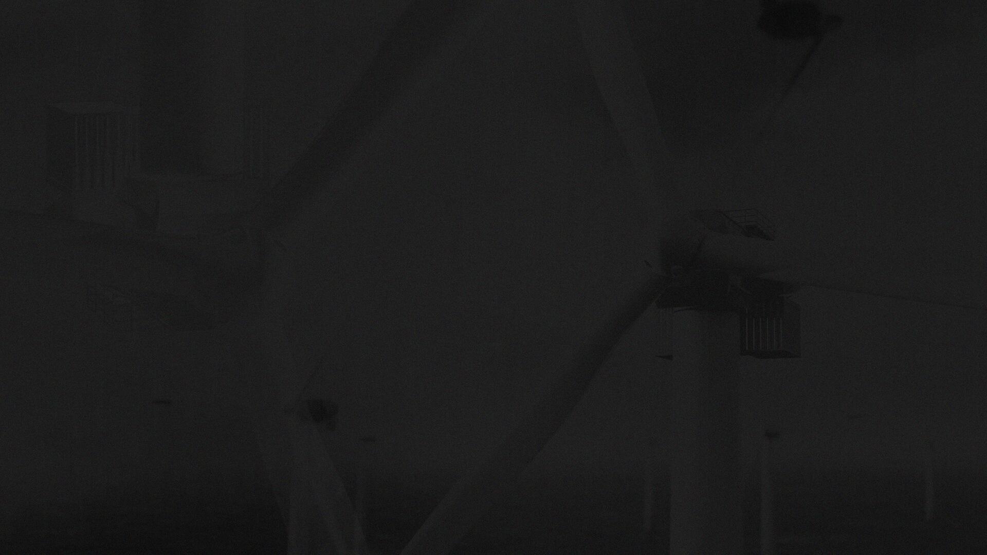 Wind turbines against a dark, cloudy sky, with large blades and towers partially visible, creating a moody and industrial atmosphere.